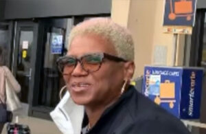 Black woman with short blonde hair and glasses